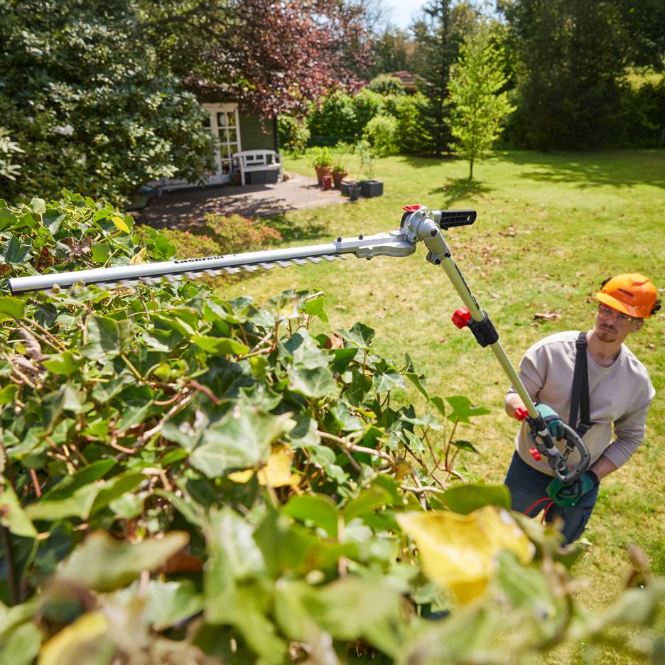 Man trimming a hedge with a Parkside telescopic hedge trimmer.