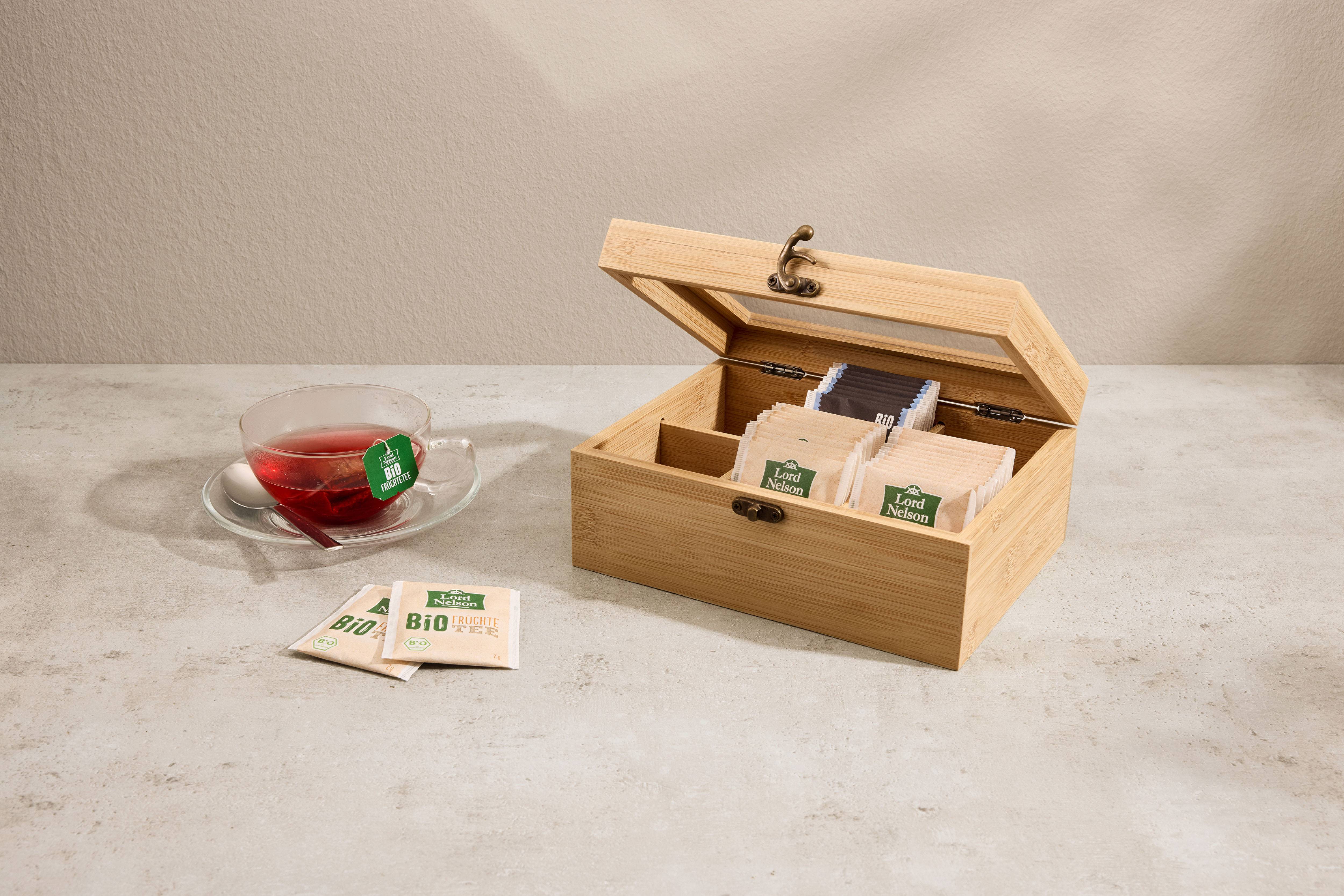 Glass teacup and wooden tea box with tea bags.