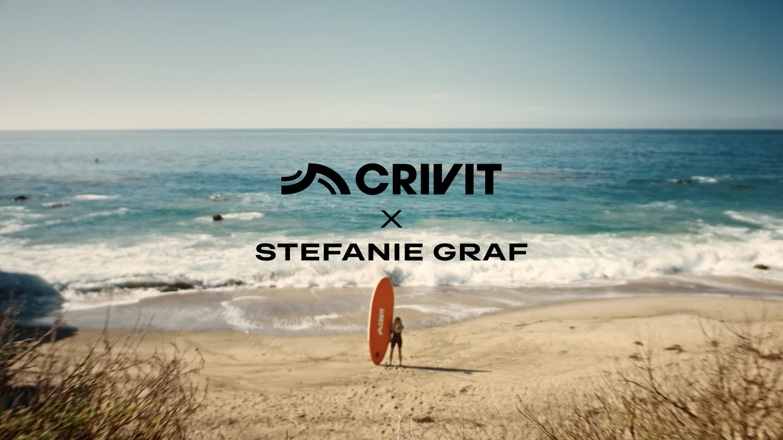 Woman with an orange SUP board on a sandy beach, with the sea in the background.