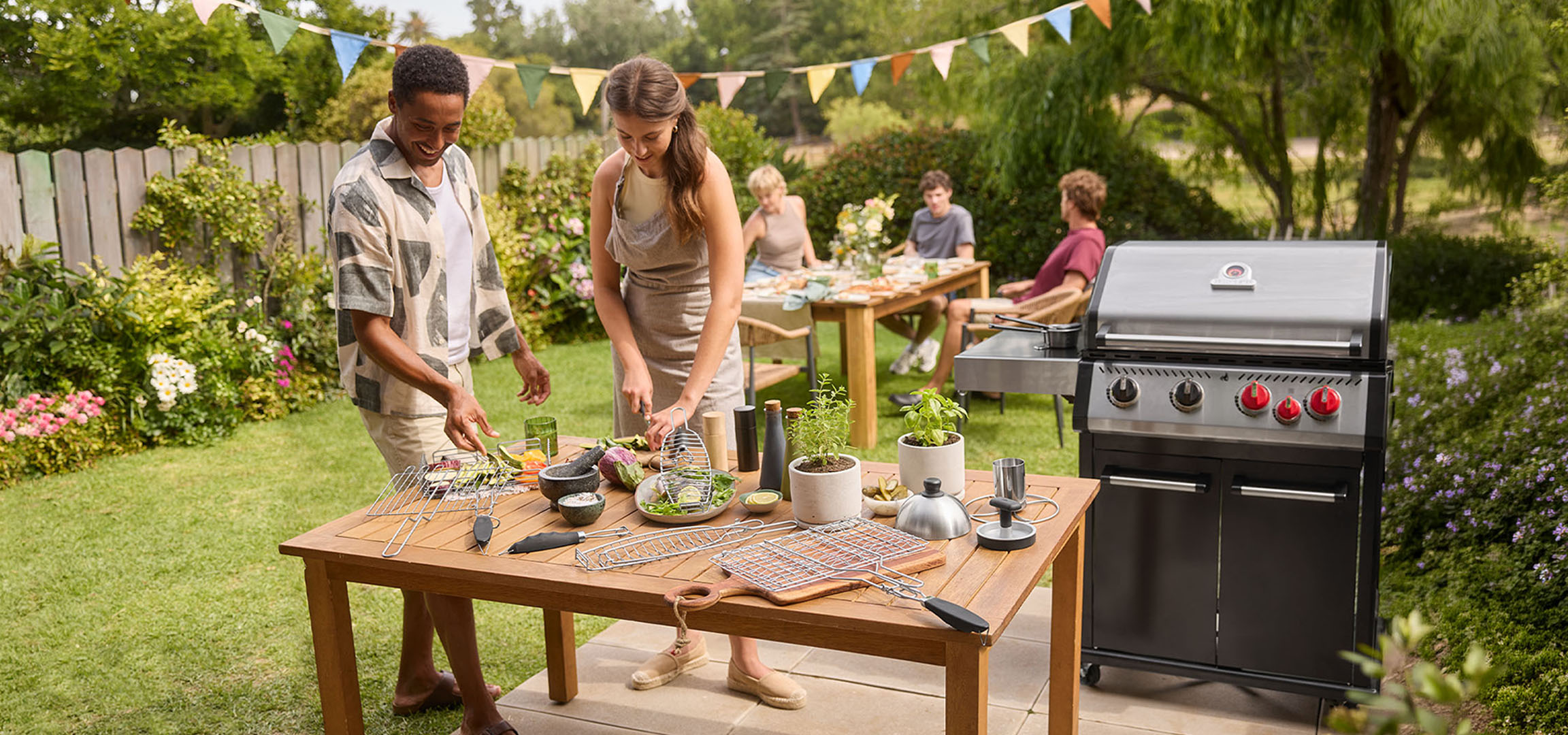 People preparing food on a barbecue in the garden, with a gas grill and table.