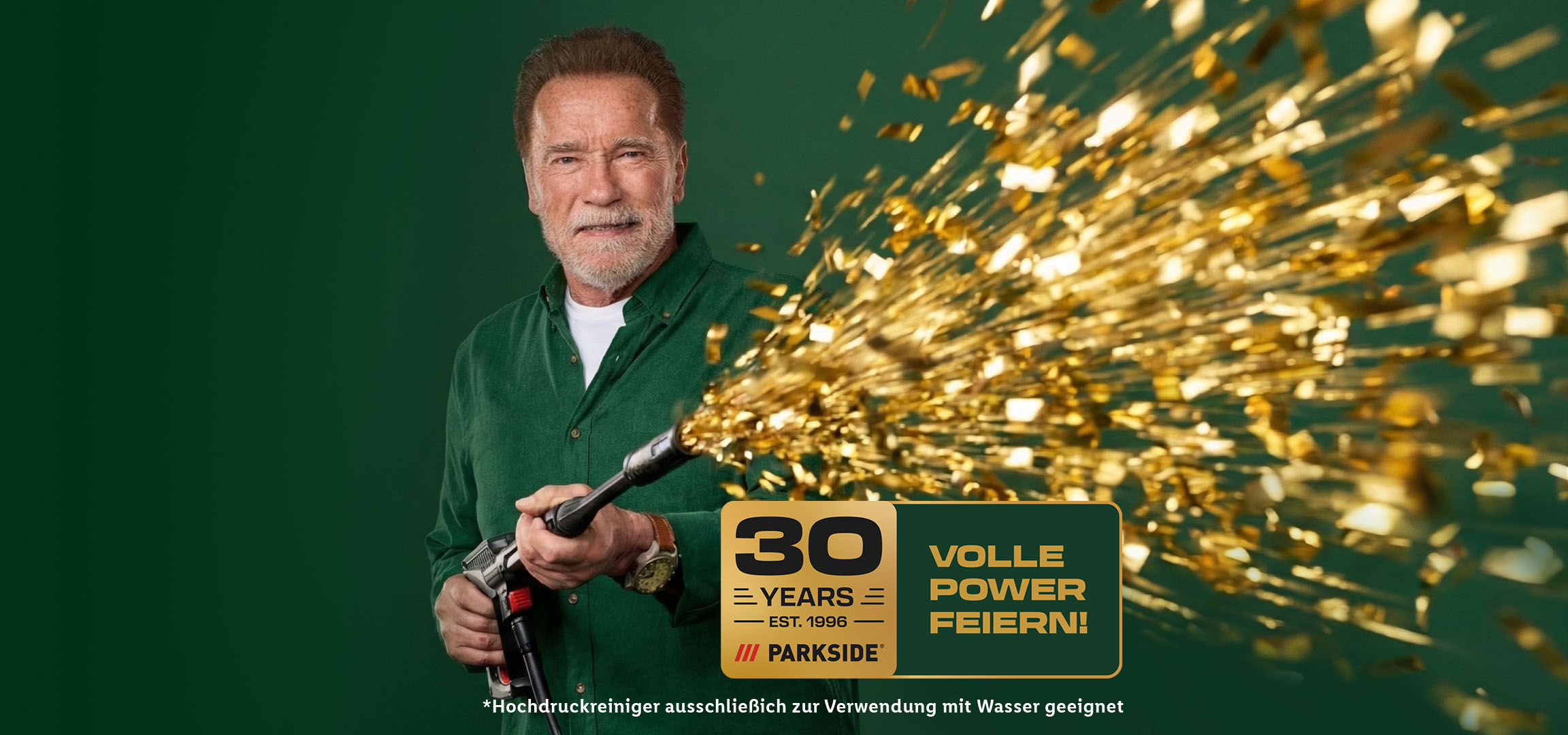 Bearded man in green shirt shoots golden confetti, celebrating 30 years with full power.