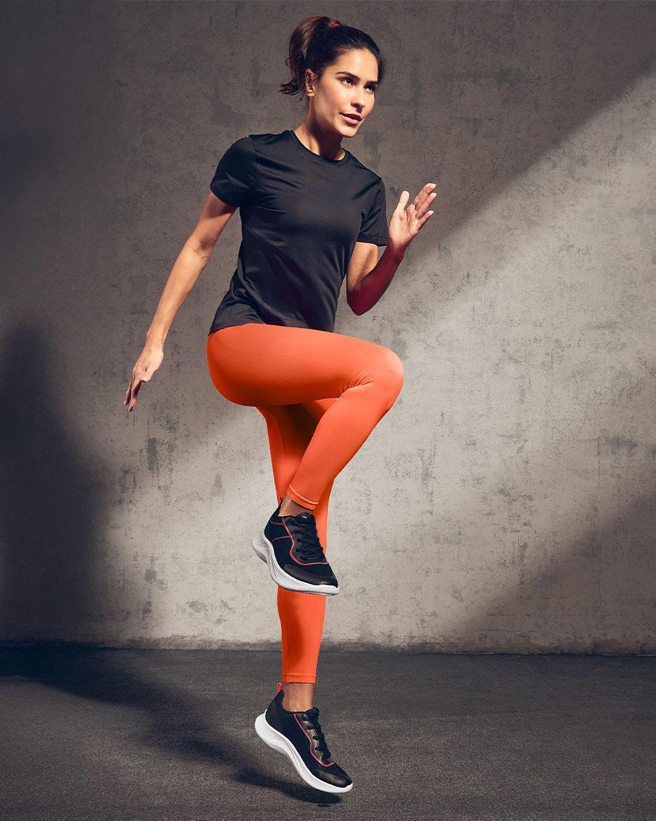 Woman in black sports t-shirt and orange leggings exercising