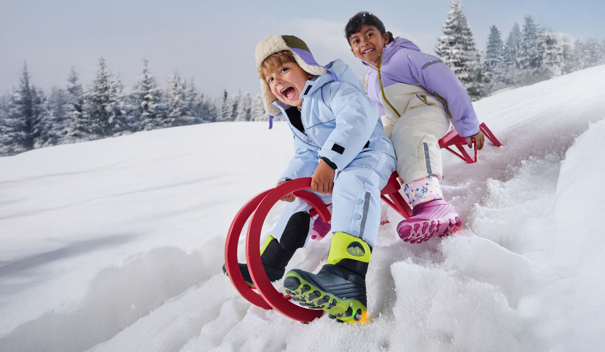 Two children in snowsuits and winter boots, sledding on snow.