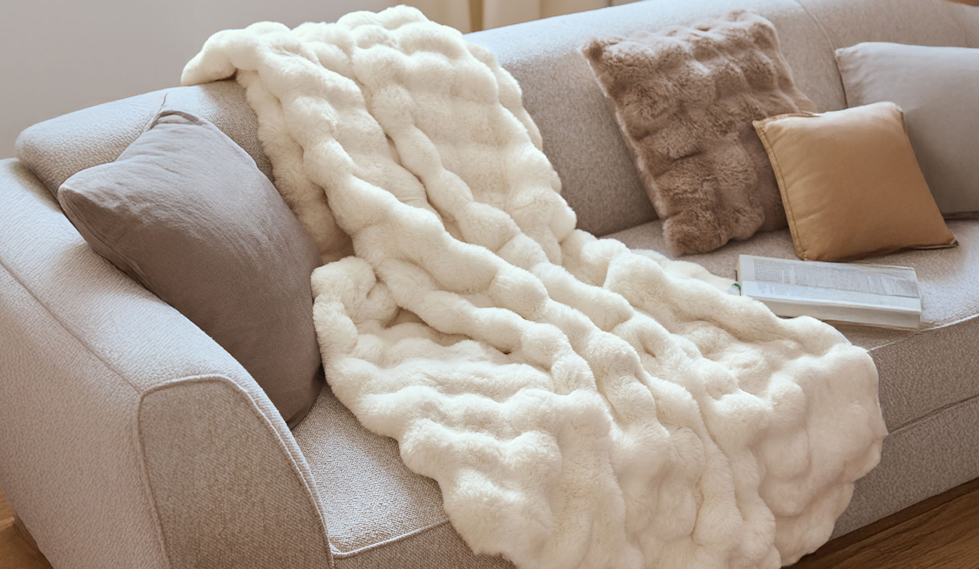 Cozy sofa with an off-white faux fur throw blanket and decorative pillows.