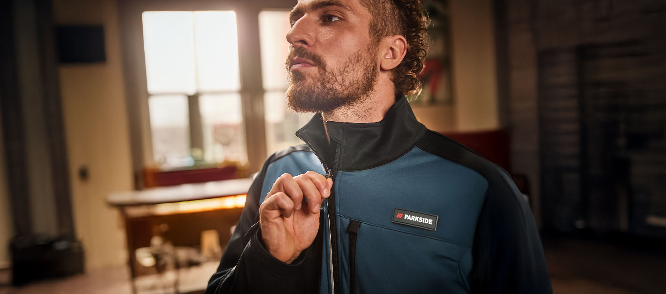 Man in a blue and black Parkside work jacket zipping it up