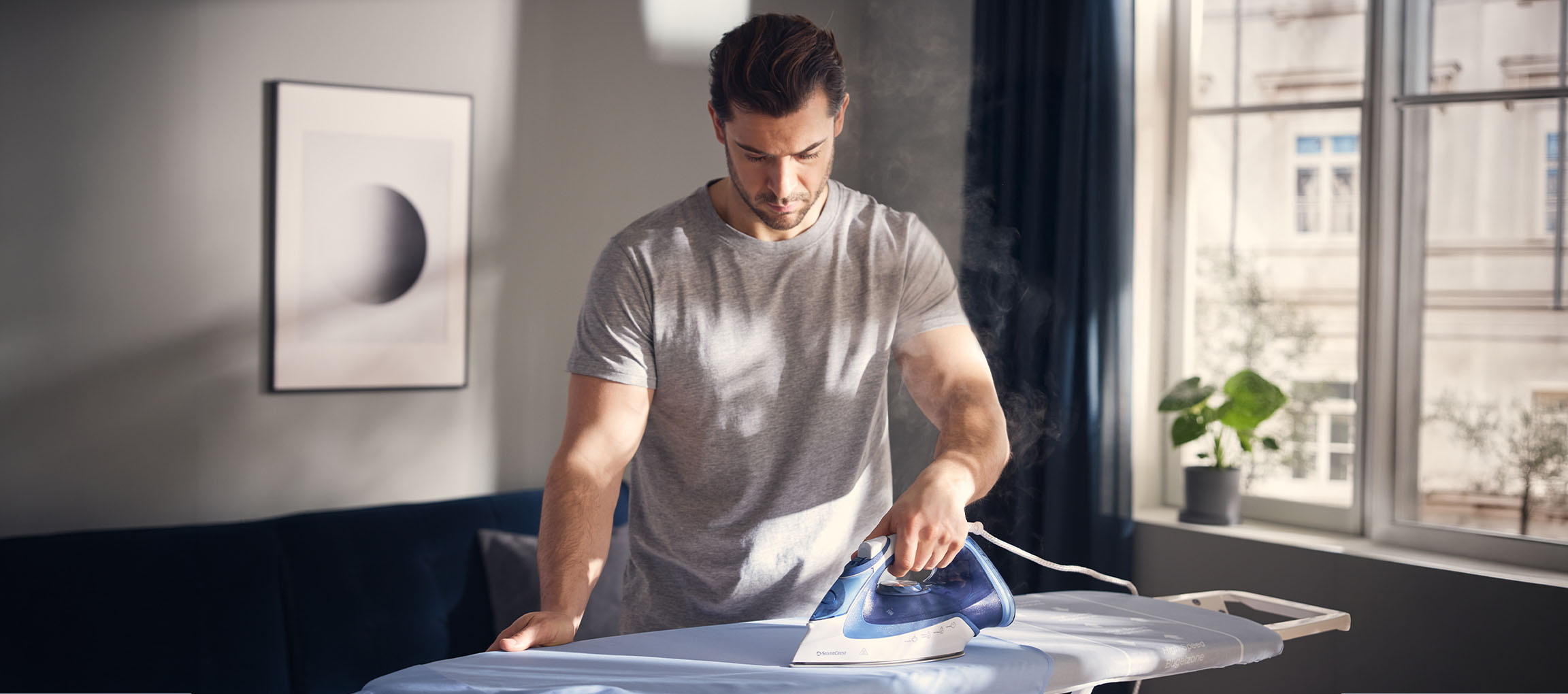 Man ironing clothes with a steam iron on an ironing board.
