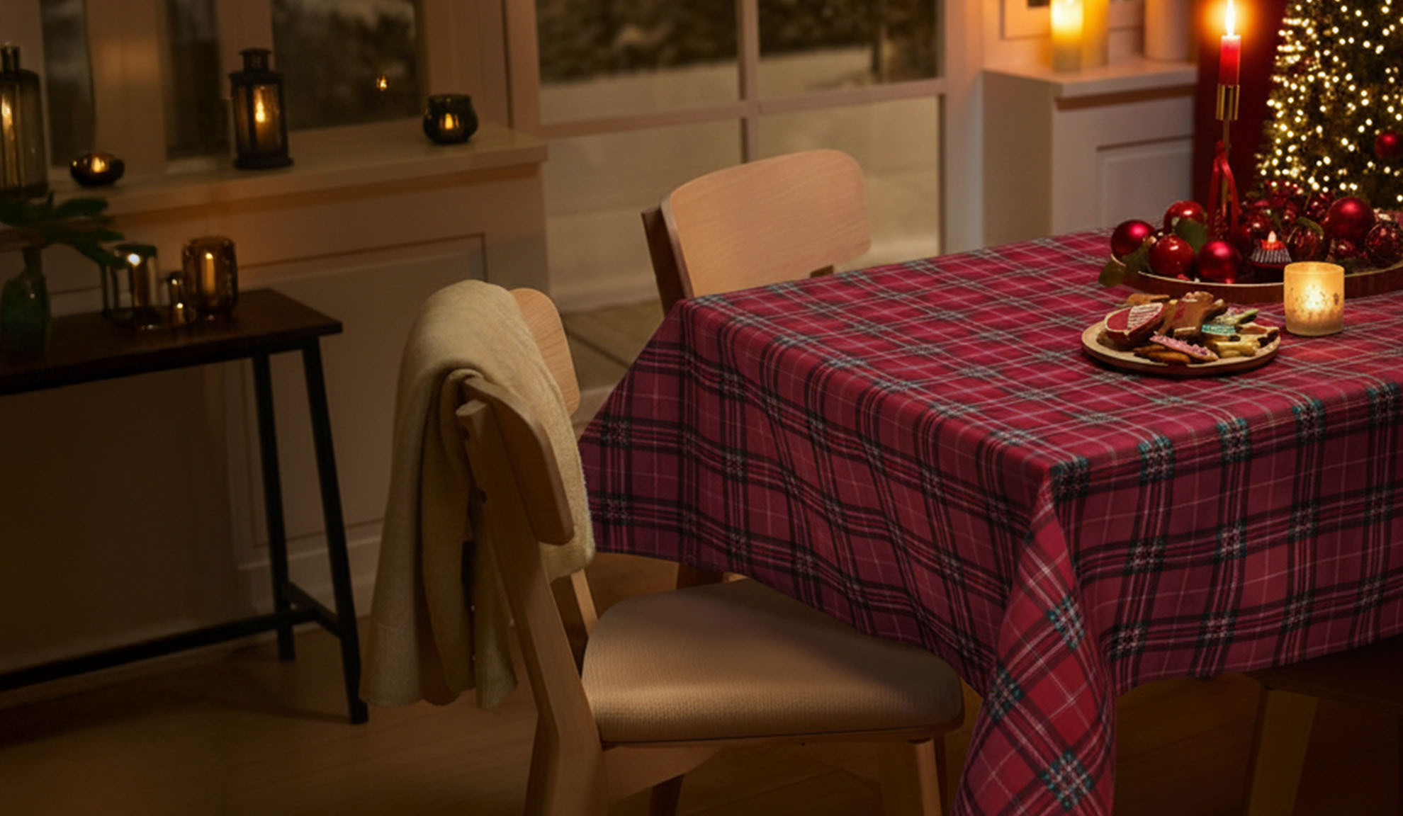 Christmas table setting with red plaid tablecloth, gingerbread cookies, and festive decorations in warm light.