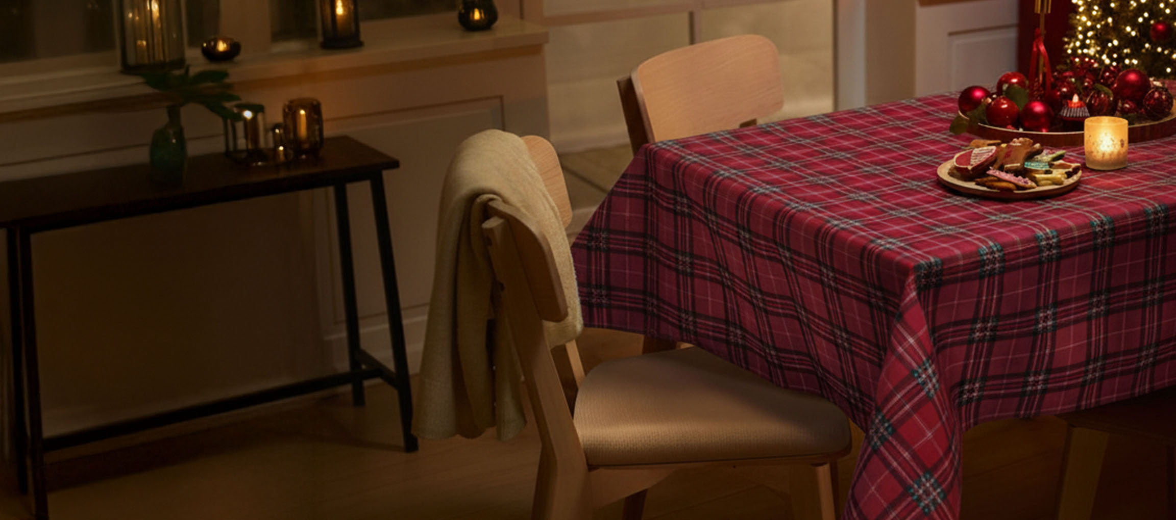 Christmas table setting with red plaid tablecloth, chairs, and Christmas cookies.