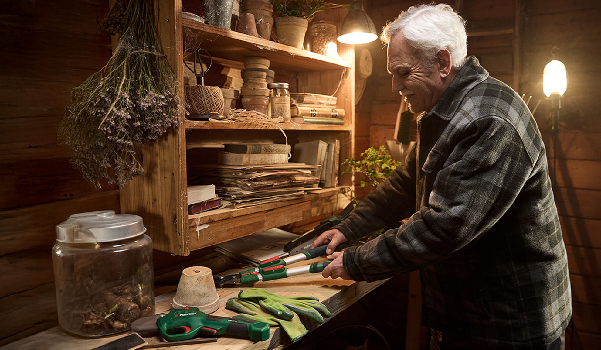 Man with Parkside loppers and gardening gloves in a shed.