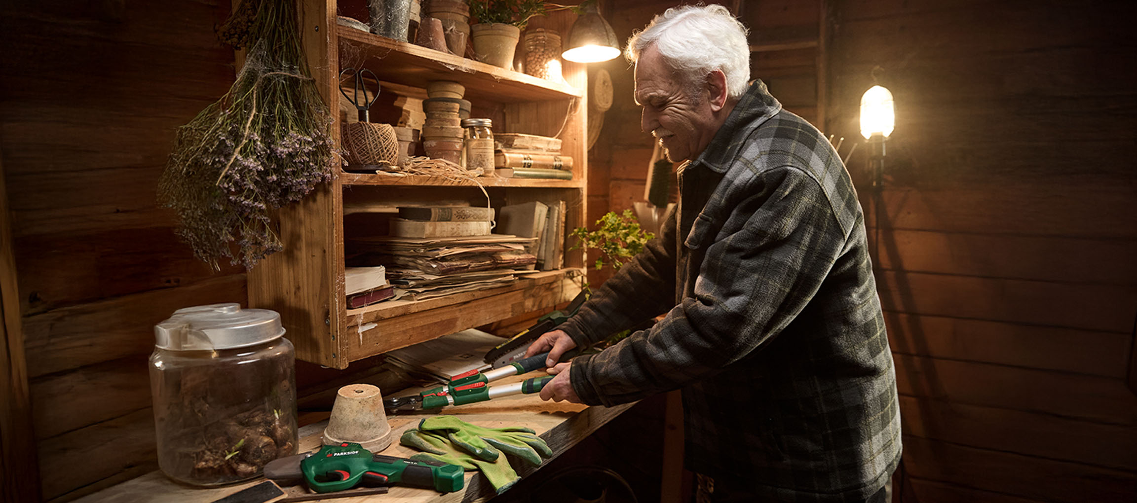 Man in a shed with Parkside loppers and gardening gloves.