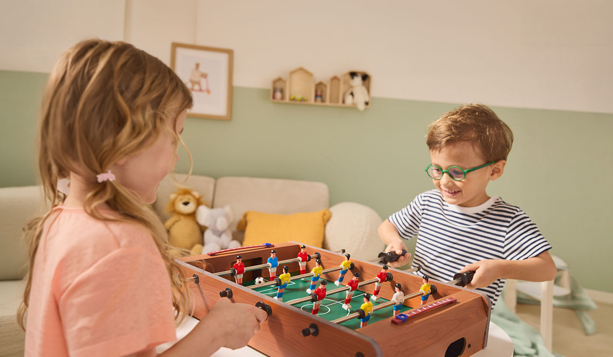 Two children playing table football, laughing happily.
