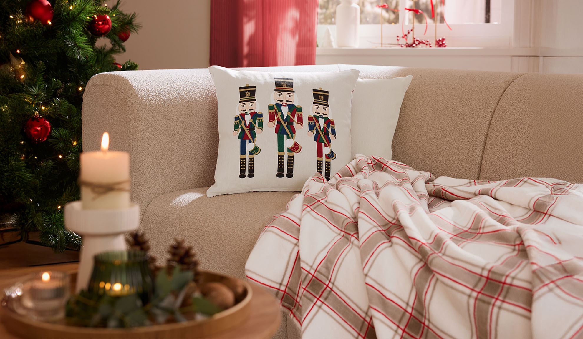 Christmas living room with a sofa, nutcracker pillows, a plaid throw, and candles.