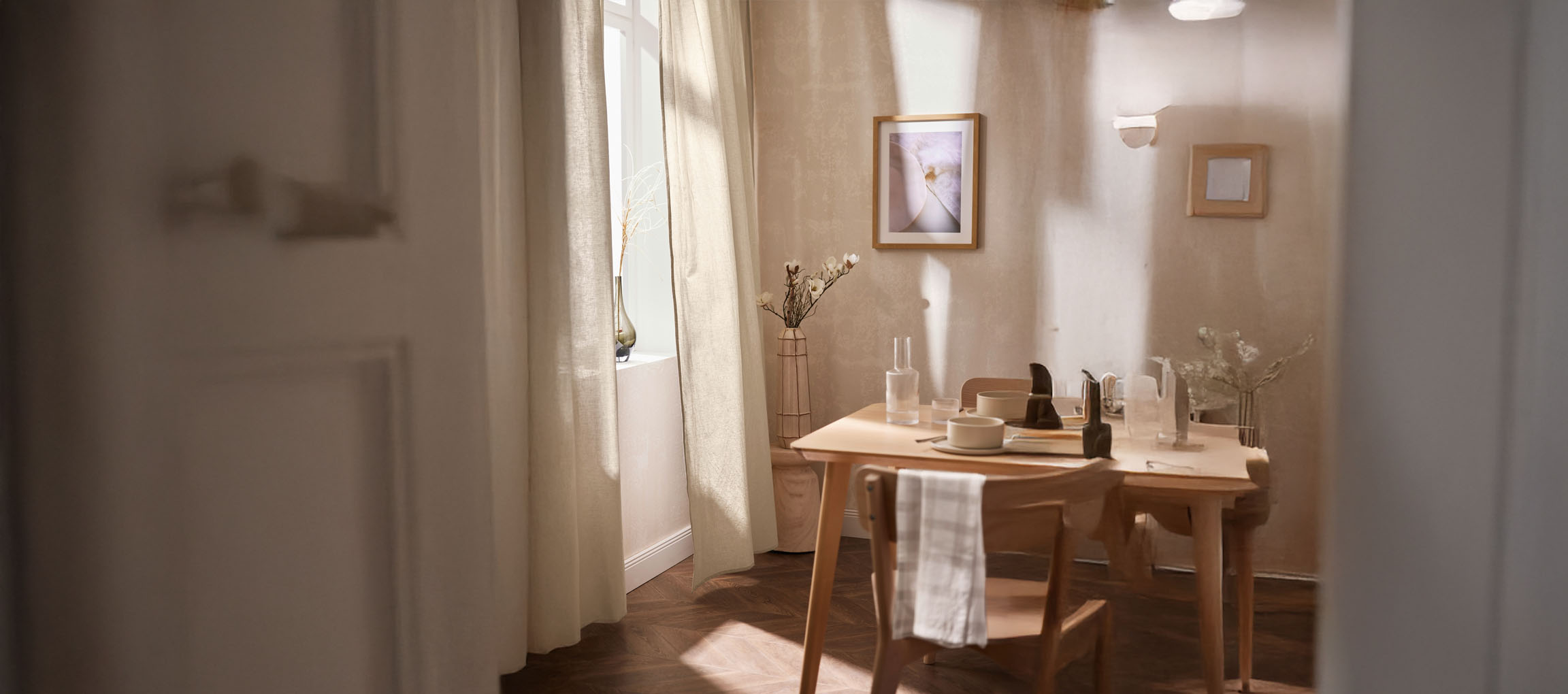 Bright dining room with a wooden table, chairs, and minimalist decorations.