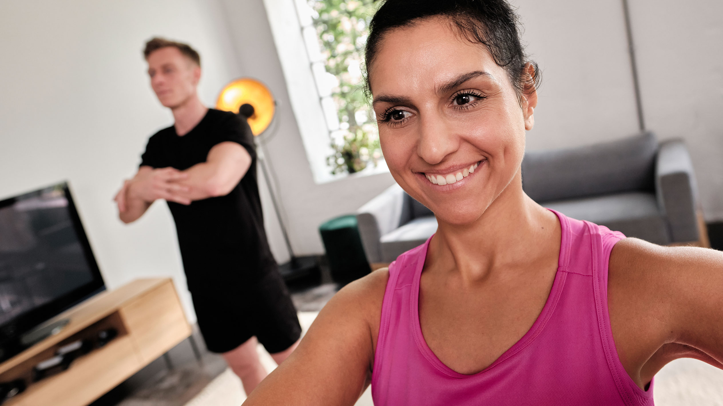 Smiling woman exercising at home with her partner.