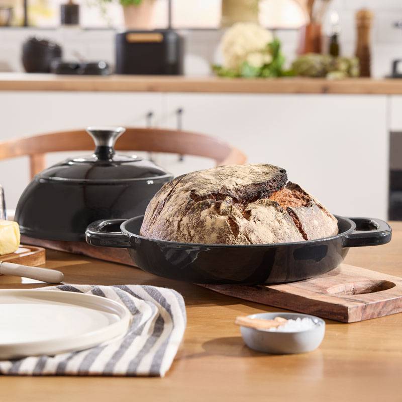 Freshly baked bread in a cast iron pot on a kitchen table.